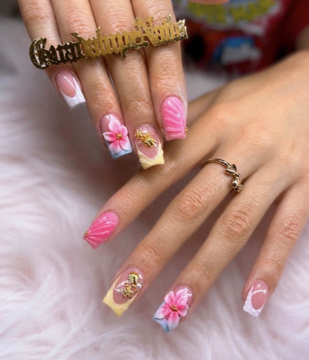 Square nails with pink French tips, painted hibiscus flowers and gold charms