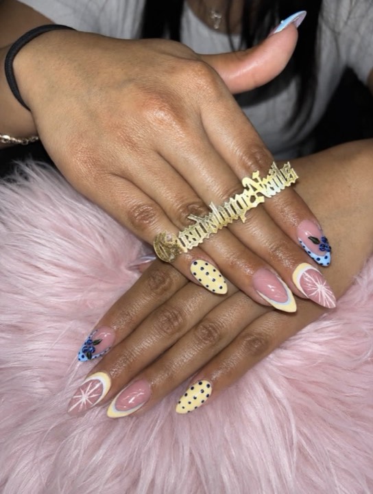 Almond nails mixing pastel yellow polka dots, French tips and blue florals